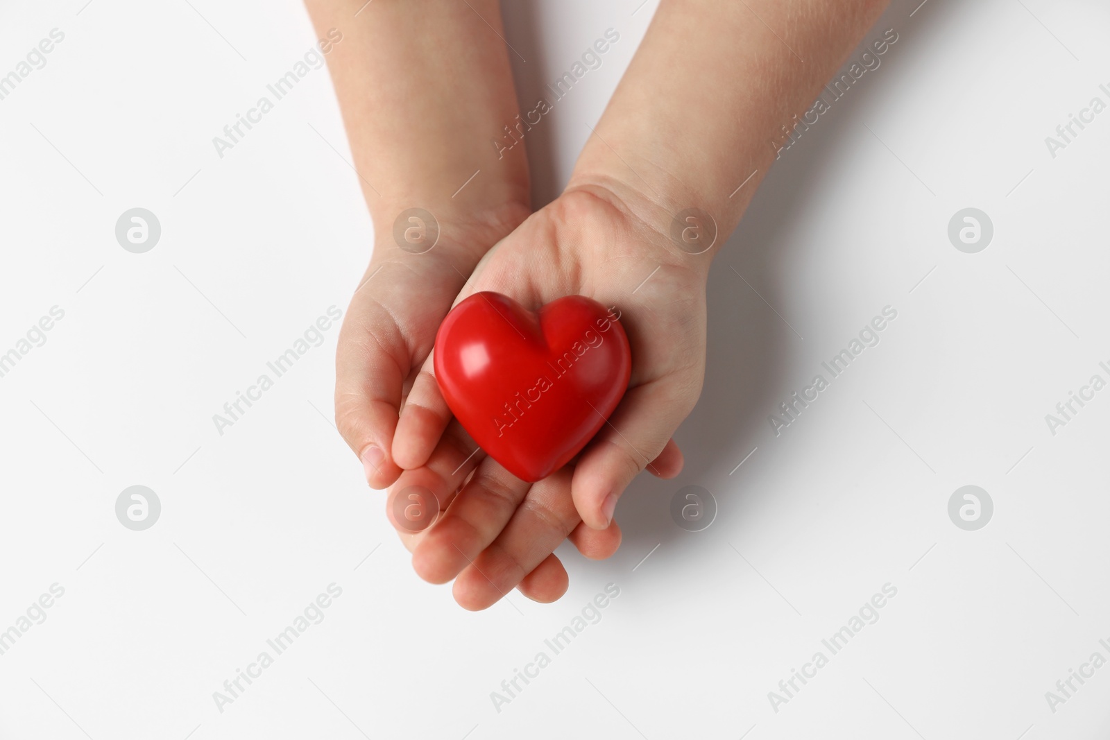 Photo of Child holding decorative red heart on white background, top view