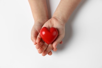 Photo of Child holding decorative red heart on white background, top view