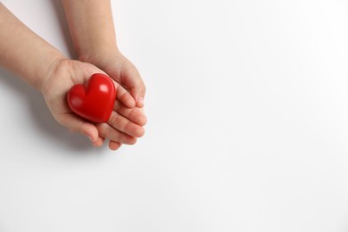 Photo of Child holding decorative red heart on white background, top view. Space for text