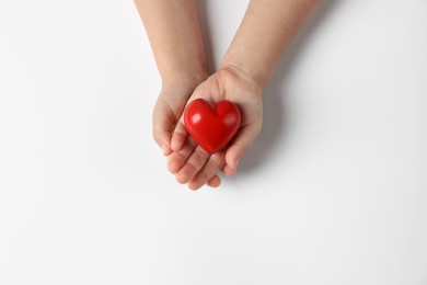 Photo of Child holding decorative red heart on white background, top view