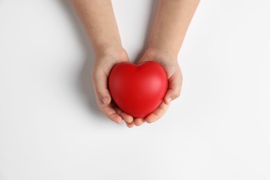 Photo of Child holding decorative red heart on white background, top view