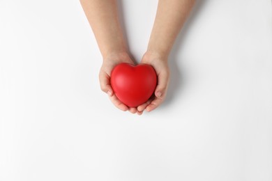 Photo of Child holding decorative red heart on white background, top view