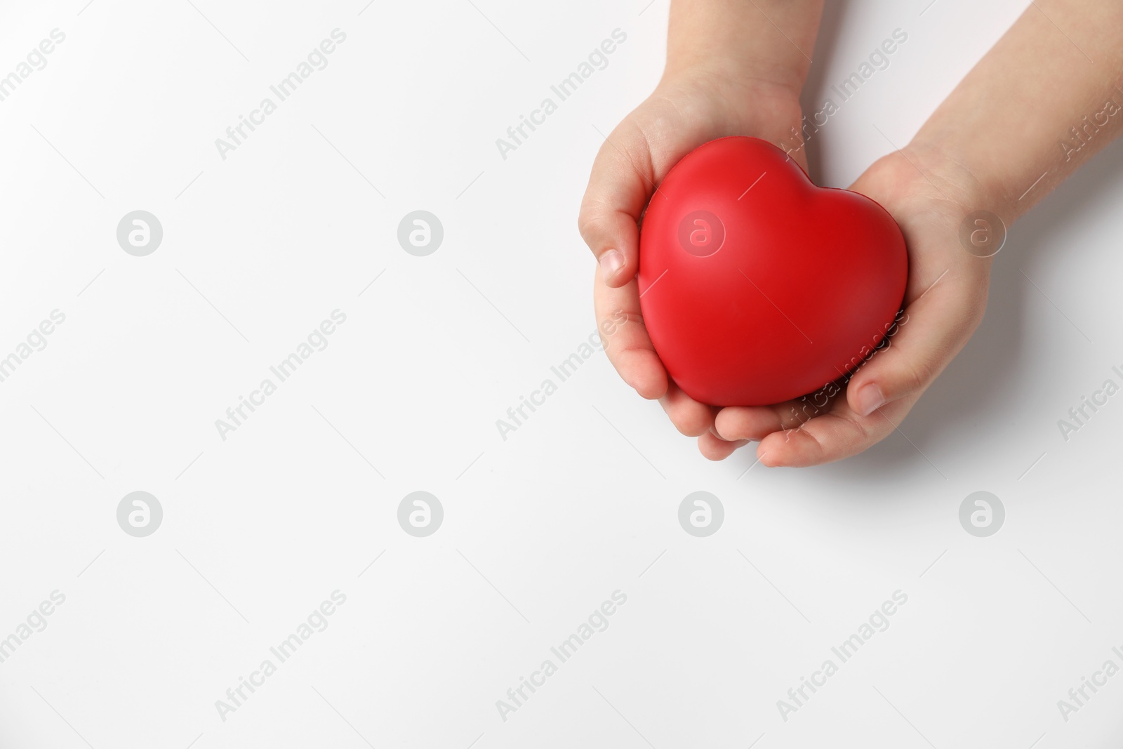 Photo of Child holding decorative red heart on white background, top view. Space for text