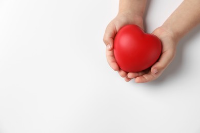 Photo of Child holding decorative red heart on white background, top view. Space for text