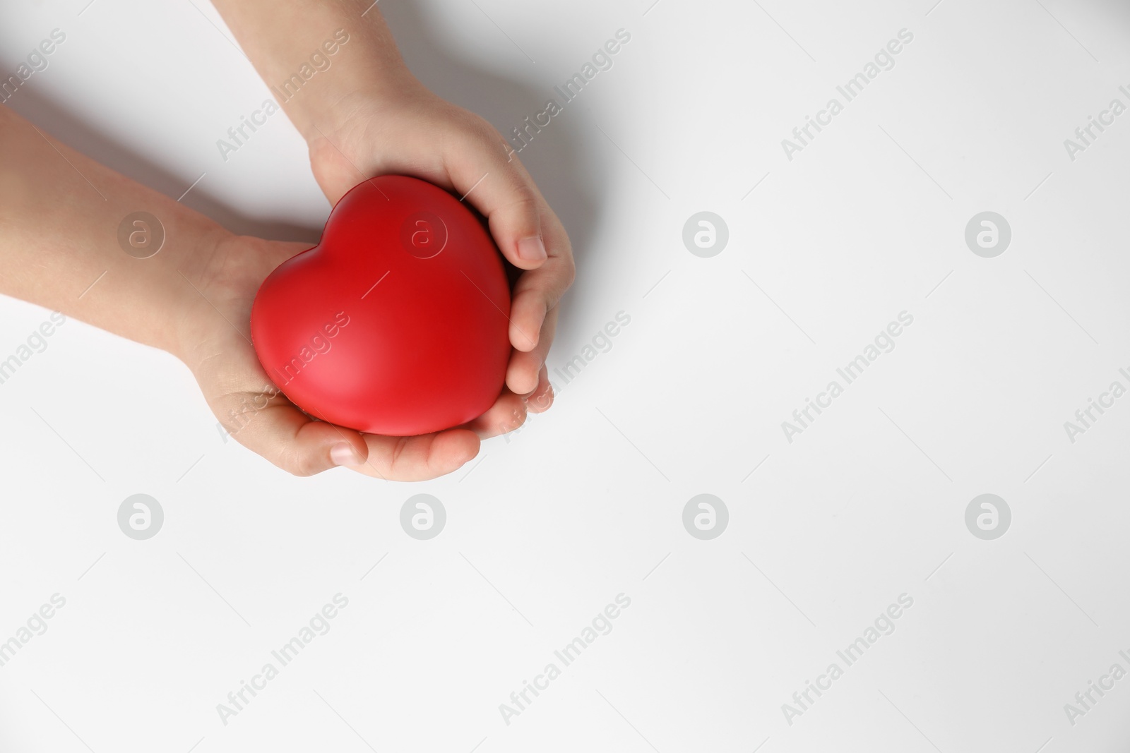 Photo of Child holding decorative red heart on white background, top view. Space for text