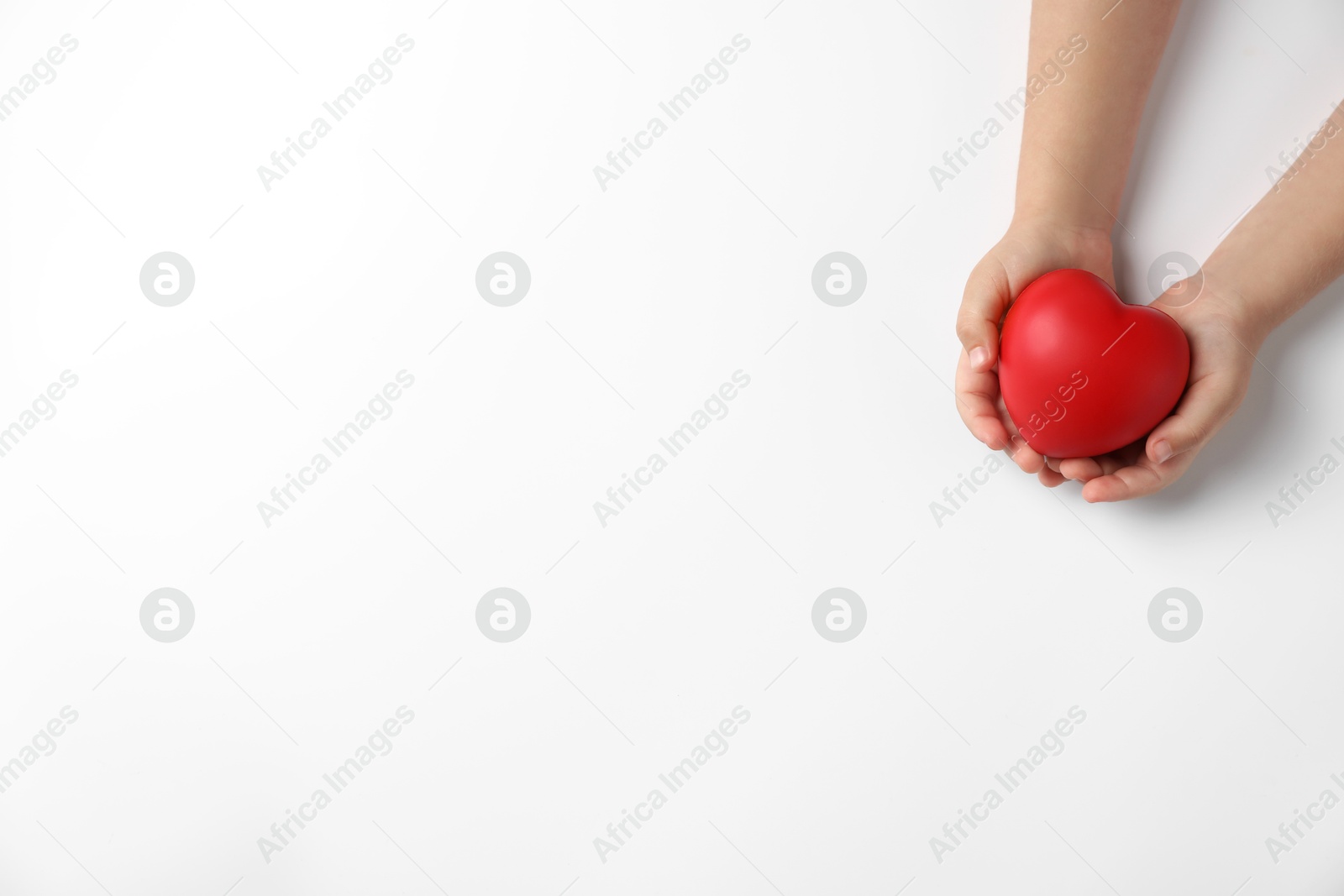 Photo of Child holding decorative red heart on white background, top view. Space for text