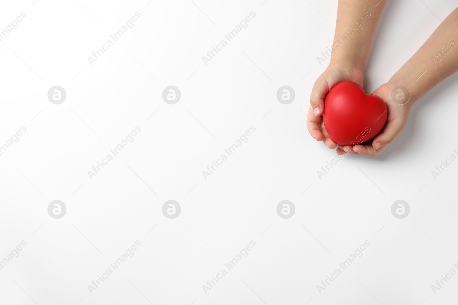 Photo of Child holding decorative red heart on white background, top view. Space for text