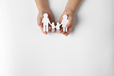 Photo of Child holding figure of family on white background, top view. Space for text