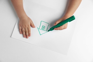 Photo of Little child drawing house with felt tip pen at light table, top view