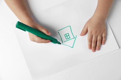 Photo of Little child drawing house with felt tip pen at light table, top view