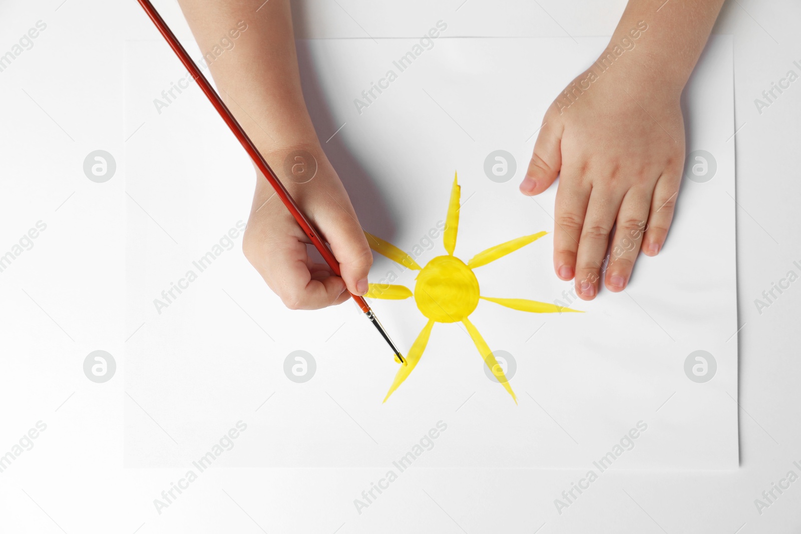 Photo of Little child drawing sun with paint at light table, top view