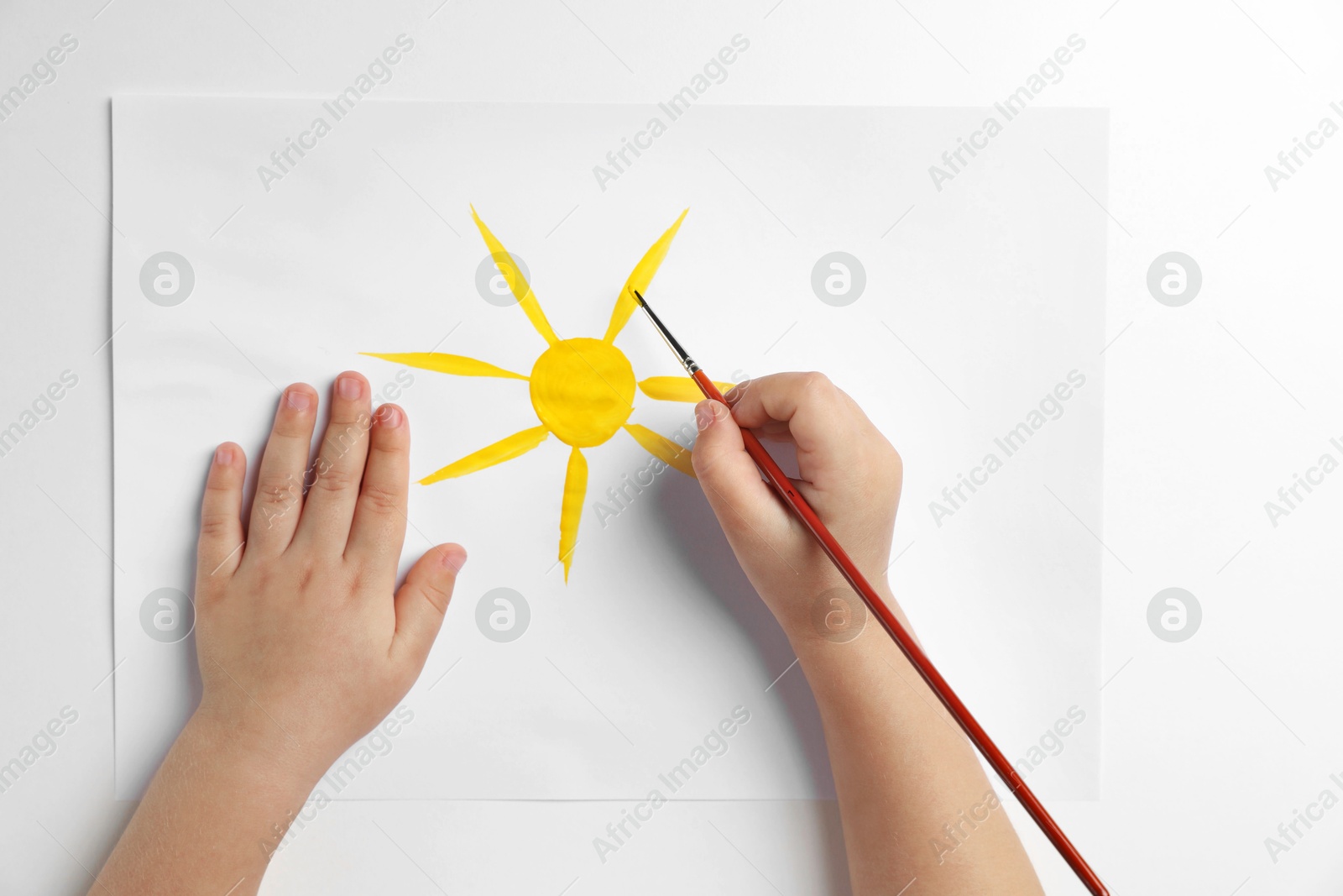 Photo of Little child drawing sun with paint at light table, top view