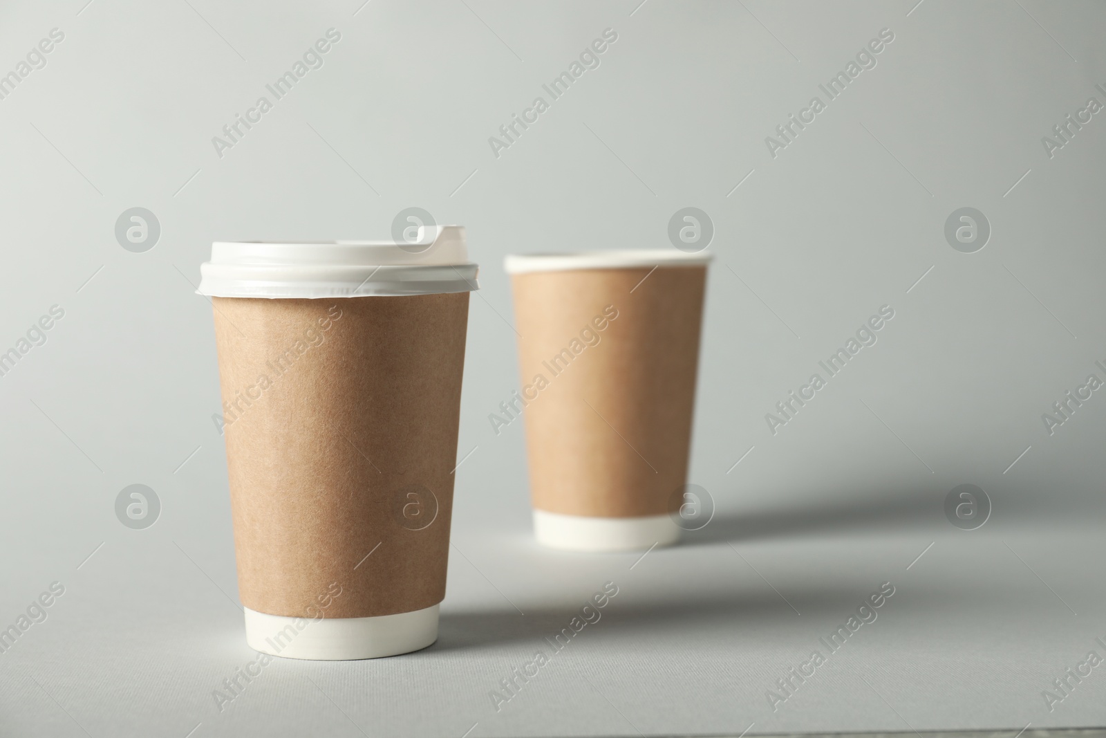 Paper cups on grey background, selective focus. Mockup for design Photo of Paper cups on grey background, selective focus. Mockup for design