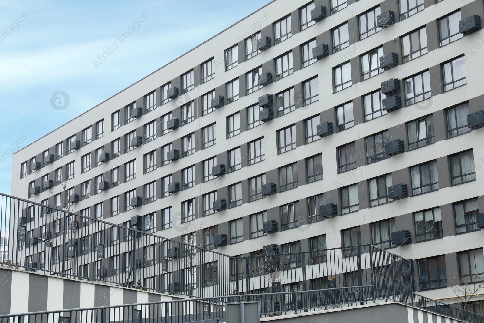 Photo of Modern building with many windows against blue sky, low angle view