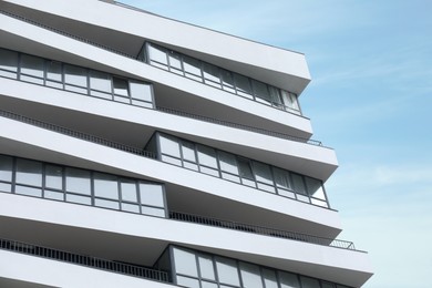 Photo of Modern building with many windows against blue sky, low angle view