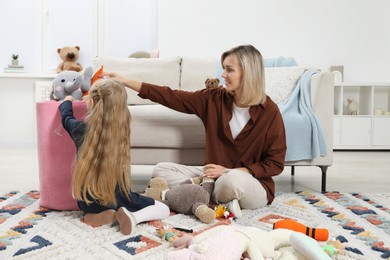 Photo of Little helper. Daughter and mother putting away toys together at home