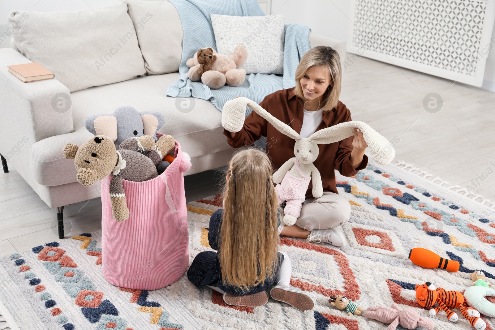 Photo of Little helper. Daughter and mother putting away toys together at home