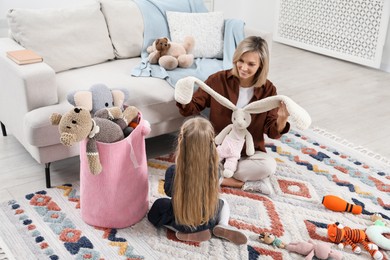 Photo of Little helper. Daughter and mother putting away toys together at home