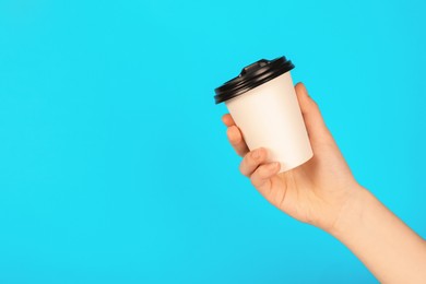 Photo of Woman holding paper cup on light blue background, closeup. Mockup for design