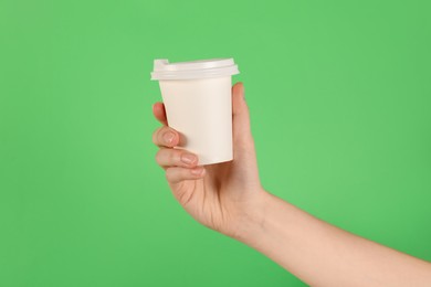 Photo of Woman holding paper cup on green background, closeup. Mockup for design