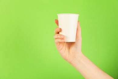 Photo of Woman holding paper cup on green background, closeup. Mockup for design