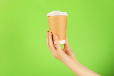 Photo of Woman holding paper cup on green background, closeup. Mockup for design