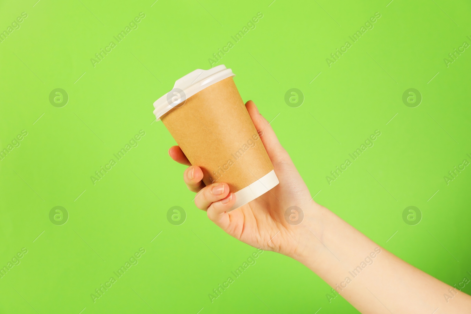 Woman holding paper cup on green background, closeup. Mockup for design Photo of Woman holding paper cup on green background, closeup. Mockup for design