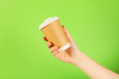 Photo of Woman holding paper cup on green background, closeup. Mockup for design