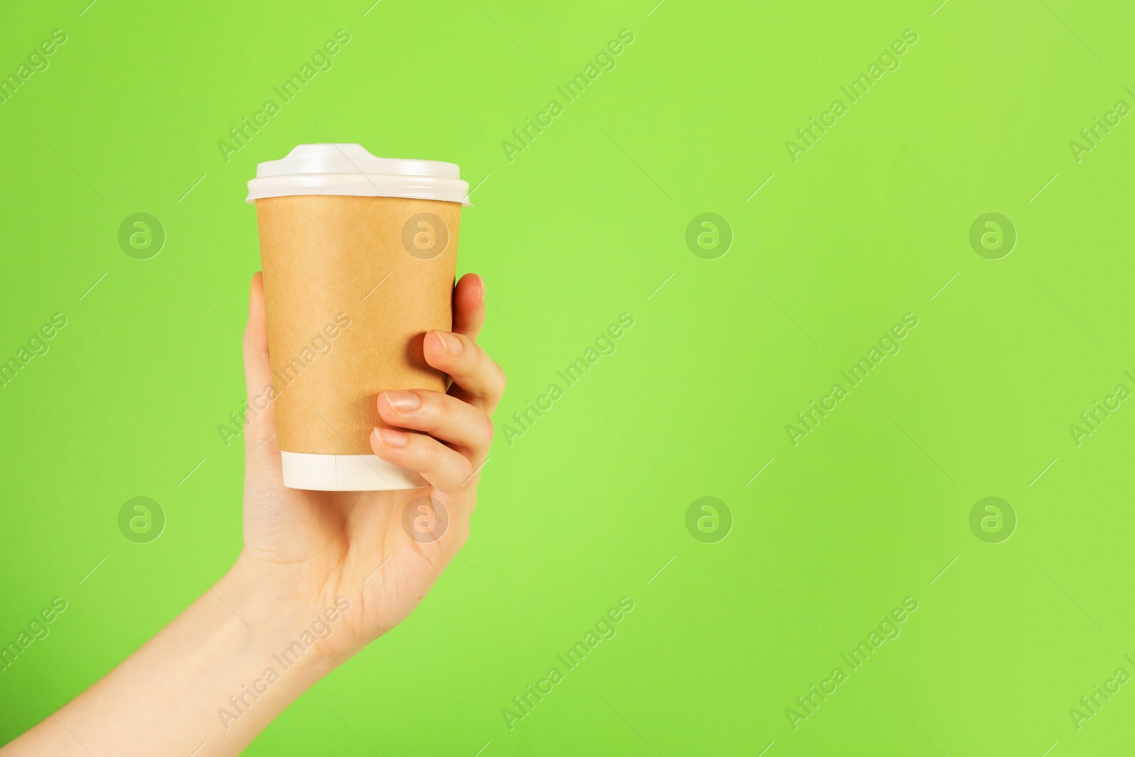 Woman holding paper cup on green background, closeup. Mockup for design Photo of Woman holding paper cup on green background, closeup. Mockup for design