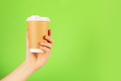 Photo of Woman holding paper cup on green background, closeup. Mockup for design