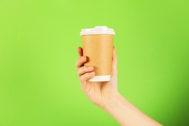 Photo of Woman holding paper cup on green background, closeup. Mockup for design