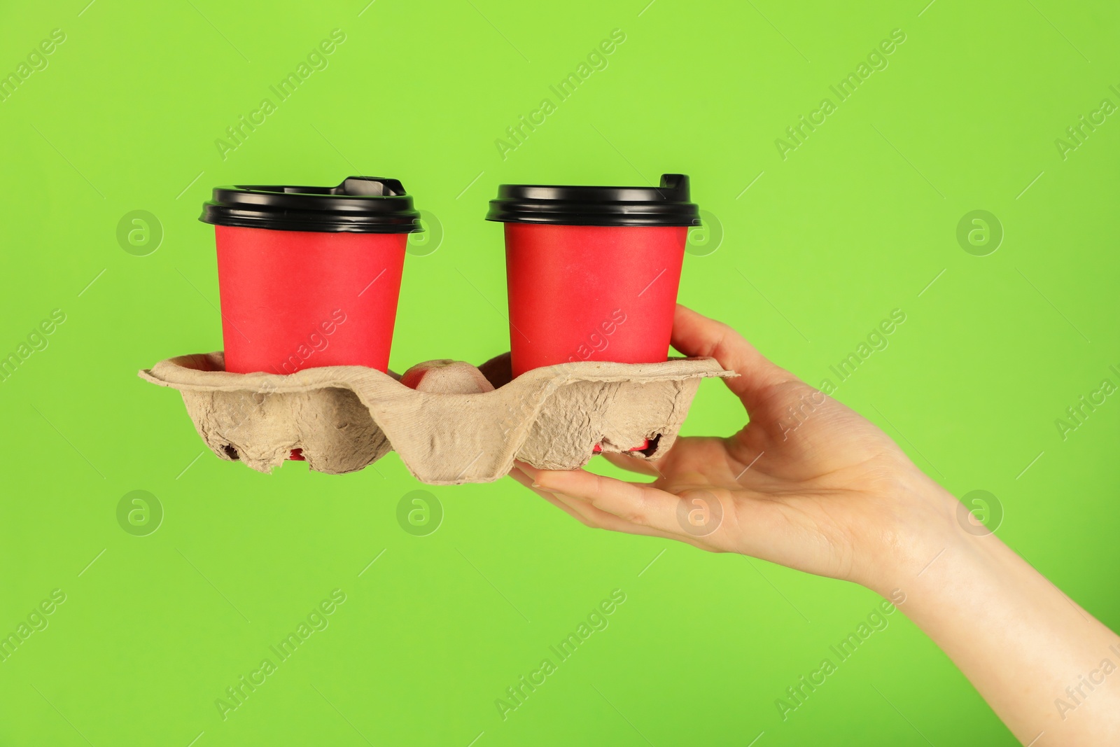 Woman holding holder with paper cups on green background, closeup. Mockup for design Photo of Woman holding holder with paper cups on green background, closeup. Mockup for design