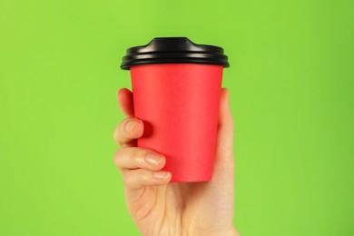 Photo of Woman holding paper cup on green background, closeup. Mockup for design