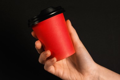 Photo of Woman holding paper cup on black background, closeup. Mockup for design