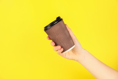 Photo of Woman holding paper cup on yellow background, closeup. Mockup for design