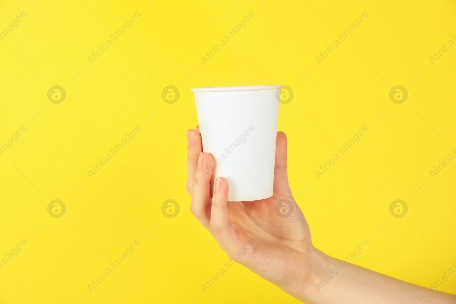 Woman holding paper cup on yellow background, closeup. Mockup for design Photo of Woman holding paper cup on yellow background, closeup. Mockup for design