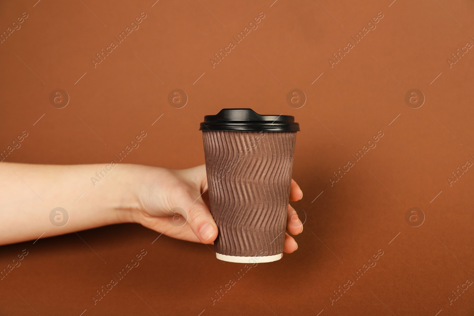 Woman holding paper cup on brown background, closeup. Mockup for design Photo of Woman holding paper cup on brown background, closeup. Mockup for design