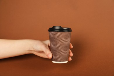 Photo of Woman holding paper cup on brown background, closeup. Mockup for design