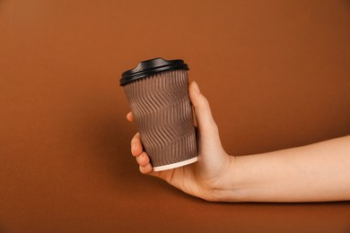 Photo of Woman holding paper cup on brown background, closeup. Mockup for design