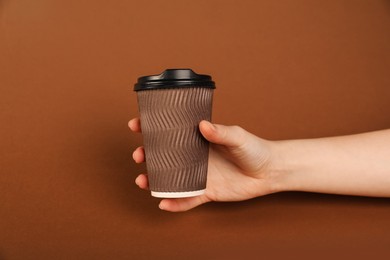 Photo of Woman holding paper cup on brown background, closeup. Mockup for design