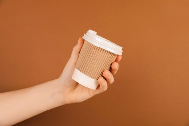 Photo of Woman holding paper cup on brown background, closeup. Mockup for design