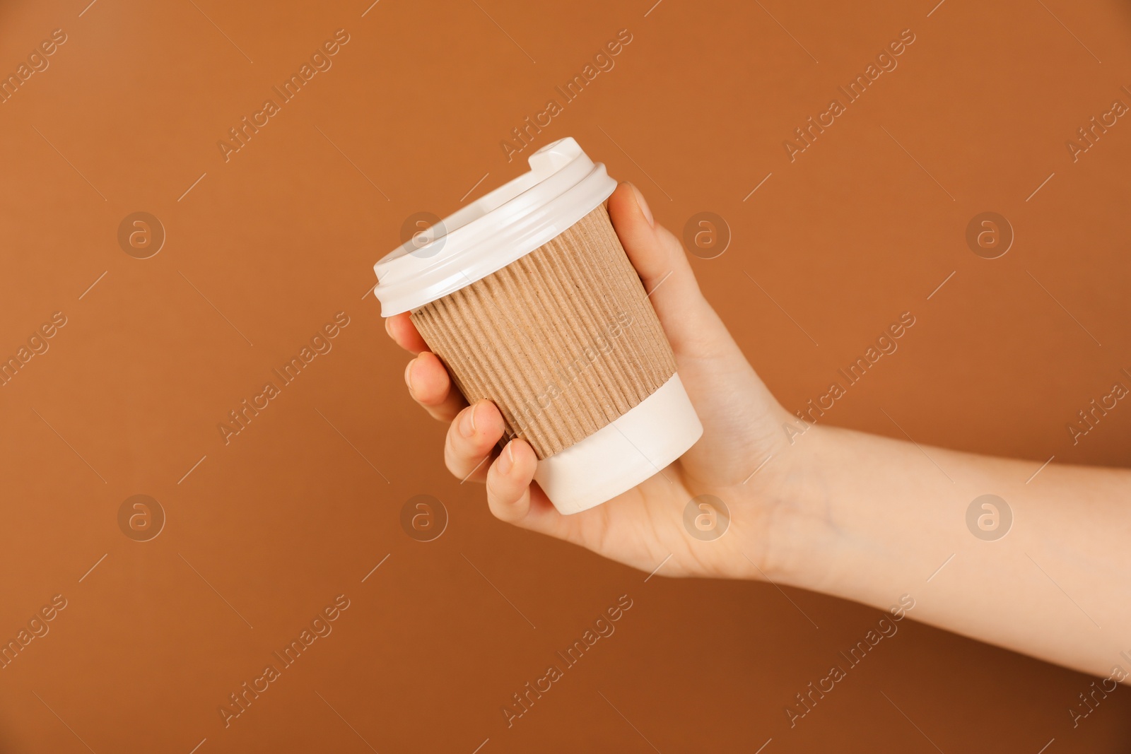 Woman holding paper cup on brown background, closeup. Mockup for design Photo of Woman holding paper cup on brown background, closeup. Mockup for design