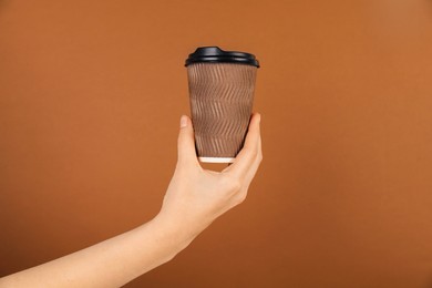 Photo of Woman holding paper cup on brown background, closeup. Mockup for design