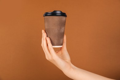 Photo of Woman holding paper cup on brown background, closeup. Mockup for design