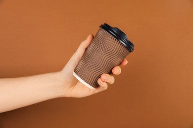 Photo of Woman holding paper cup on brown background, closeup. Mockup for design
