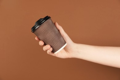 Photo of Woman holding paper cup on brown background, closeup. Mockup for design