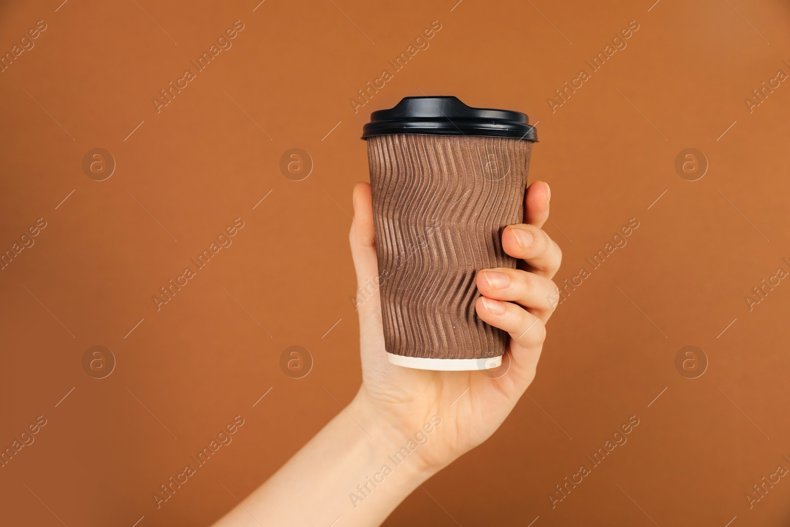 Woman holding paper cup on brown background, closeup. Mockup for design Photo of Woman holding paper cup on brown background, closeup. Mockup for design