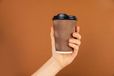 Photo of Woman holding paper cup on brown background, closeup. Mockup for design