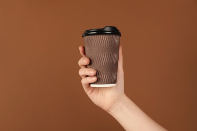 Photo of Woman holding paper cup on brown background, closeup. Mockup for design