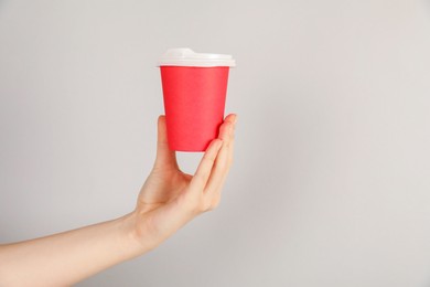 Photo of Woman holding paper cup on grey background, closeup. Mockup for design